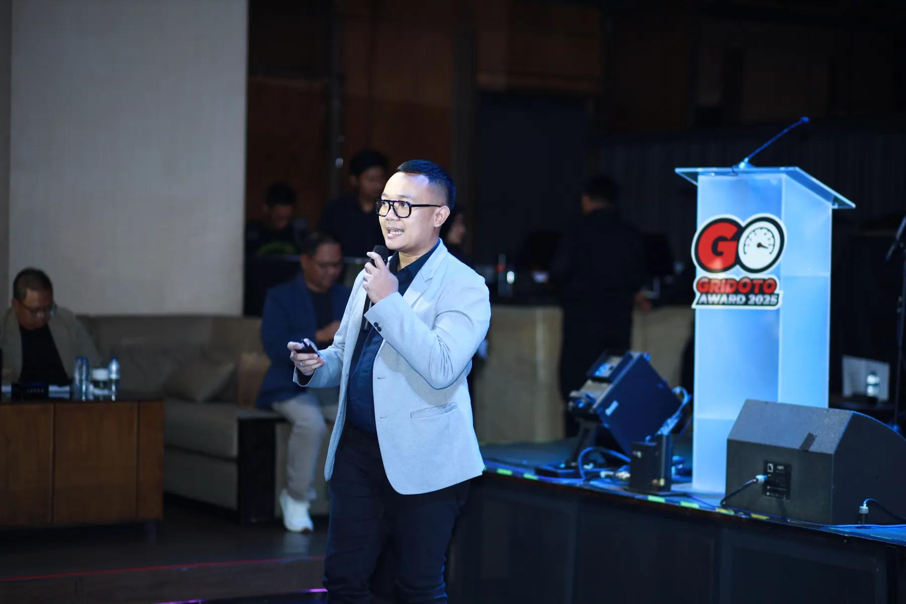 Cahyanto speaking to participants from the side of a stage.